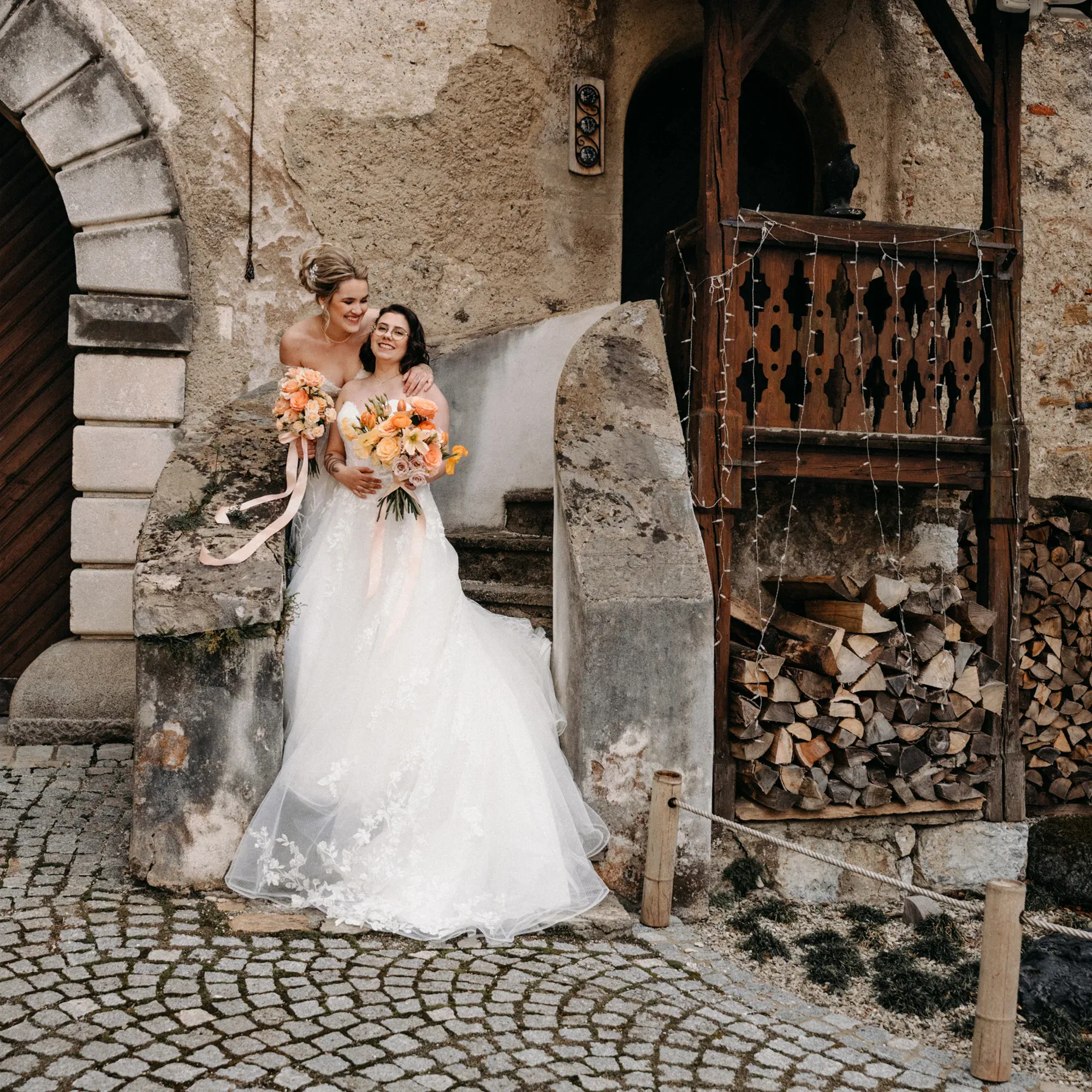 Glückliches Brautpaar in eleganten Kleidern, das vor einer antiken Mauer auf einer Hochzeit posiert.