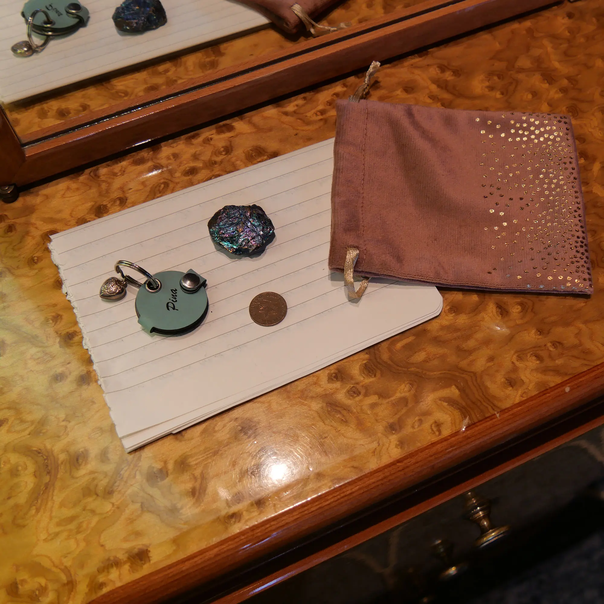 ein kleiner rosa Samtbeutel, darin ein blauer Stein und ein alter Pfennig von 1950