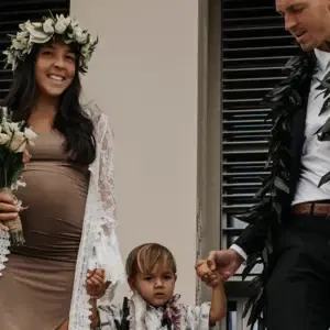 Frisch verheiratets Paar mit Kind in der Mitte und den hawaiianischen Blumenketten umgelegen.