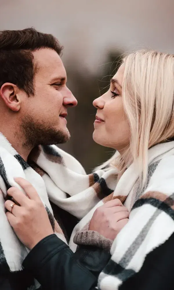 Romantisches Foto eines Paares, das sich in einen karierten Schal hüllt und innig miteinander verbunden ist.