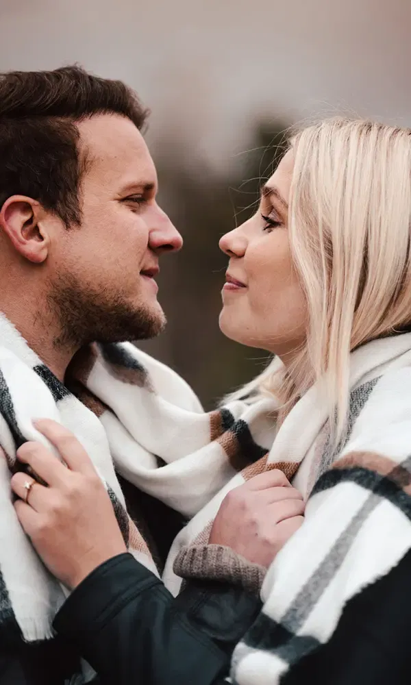 Romantisches Foto eines Paares, das sich in einen karierten Schal hüllt und innig miteinander verbunden ist.