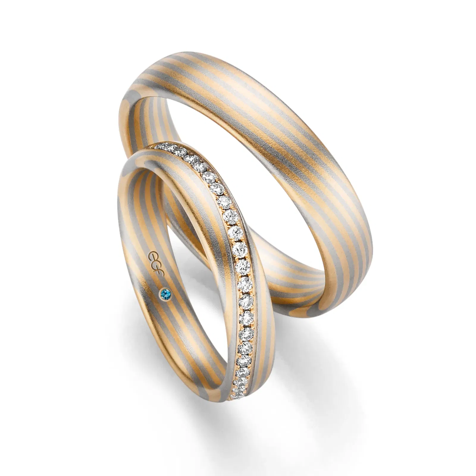 Eheringe mit Farbverlauf. Der Ring der Braut ist mit einer Reihe Diamanten besetzt.