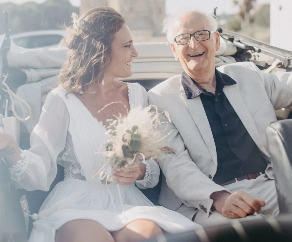 Braut mit Hochzeitsgast im Auto.
