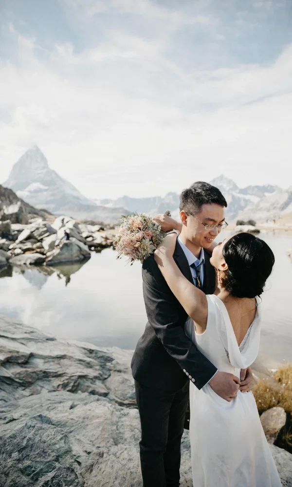 Das verliebte Brautpaar schaut sich an, im Hintergrund ein See und das Matterhorn.