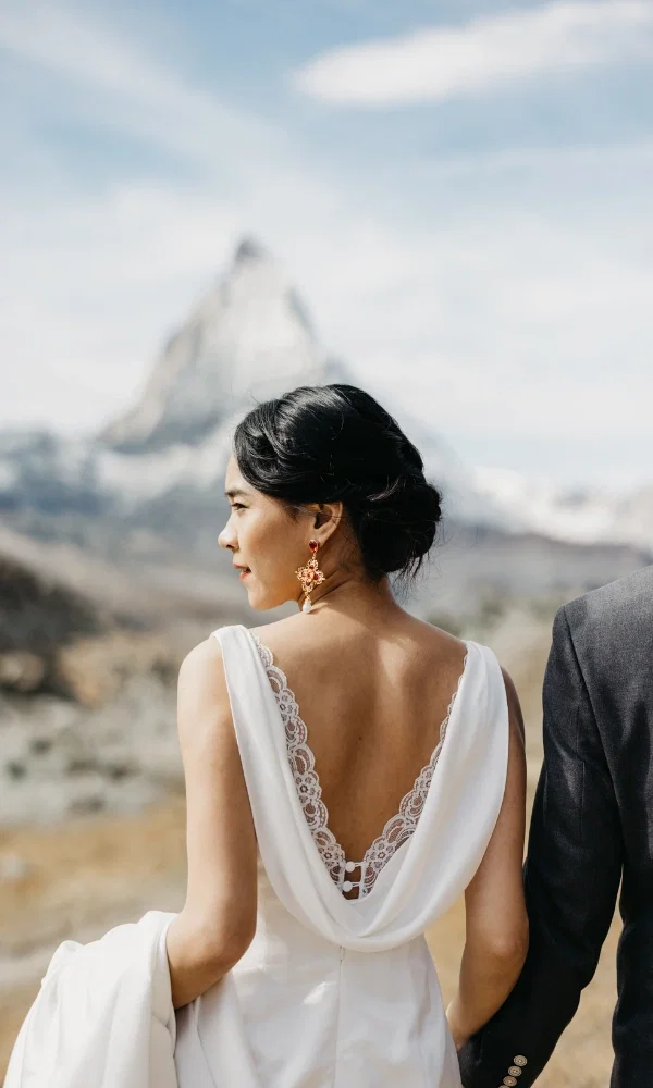 Die Braut steht im weissen Hochzeitskleid vor dem Matterhorn.