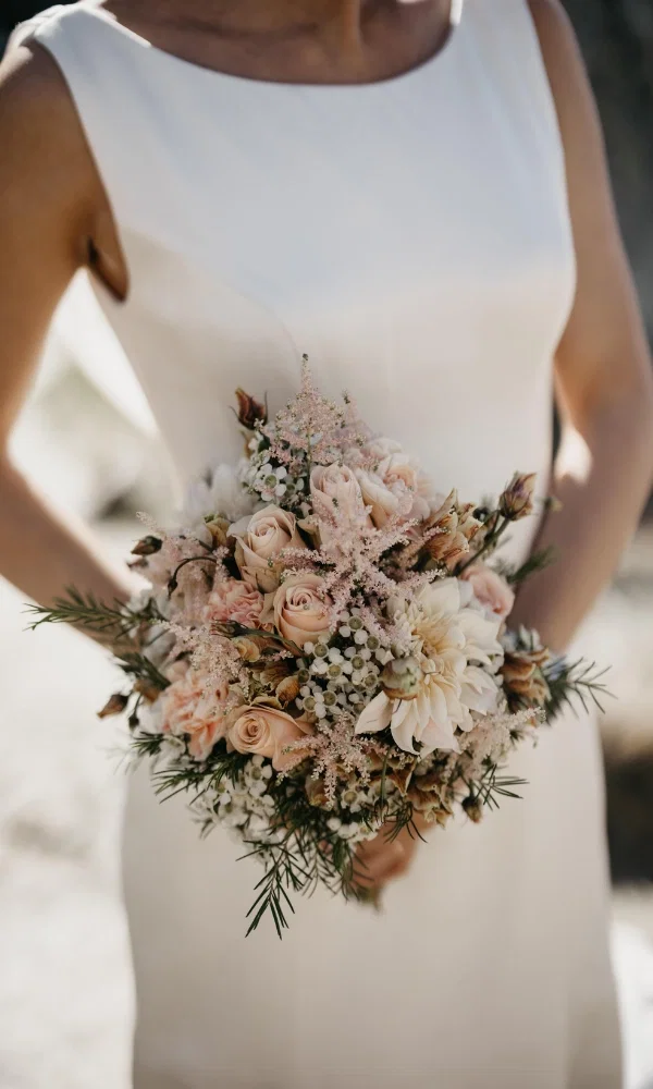 Weisses Hochzeitskleid und einen Blumenstrauss im beige Style.