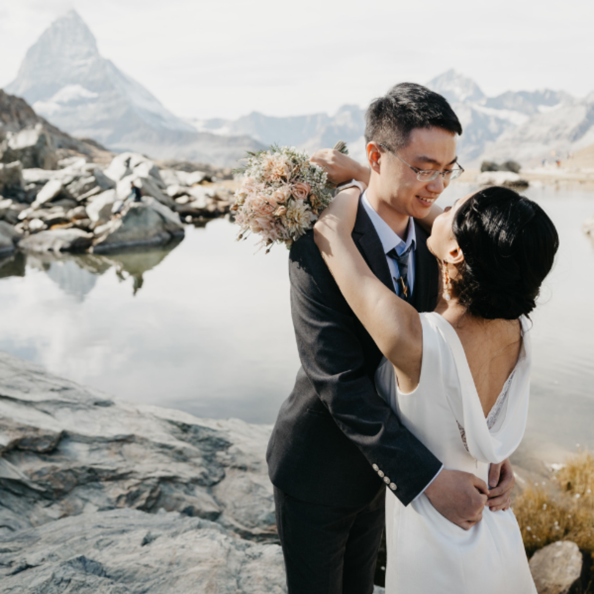 Das verliebte Brautpaar schaut sich an, im Hintergrund ein See und das Matterhorn.