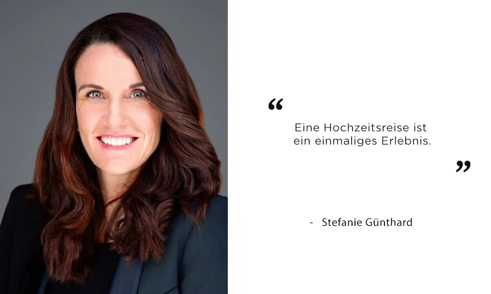 Porträt einer lächelnden Frau mit langen, dunklen Haaren vor einem neutralen Hintergrund. Rechts neben ihr steht ein Zitat: „Eine Hochzeitsreise ist ein einmaliges Erlebnis.“ – Stefanie Günthard. Die Frau trägt ein dunkles Oberteil und repräsentiert eine inspirierende Aussage zum Thema Hochzeitsreisen.