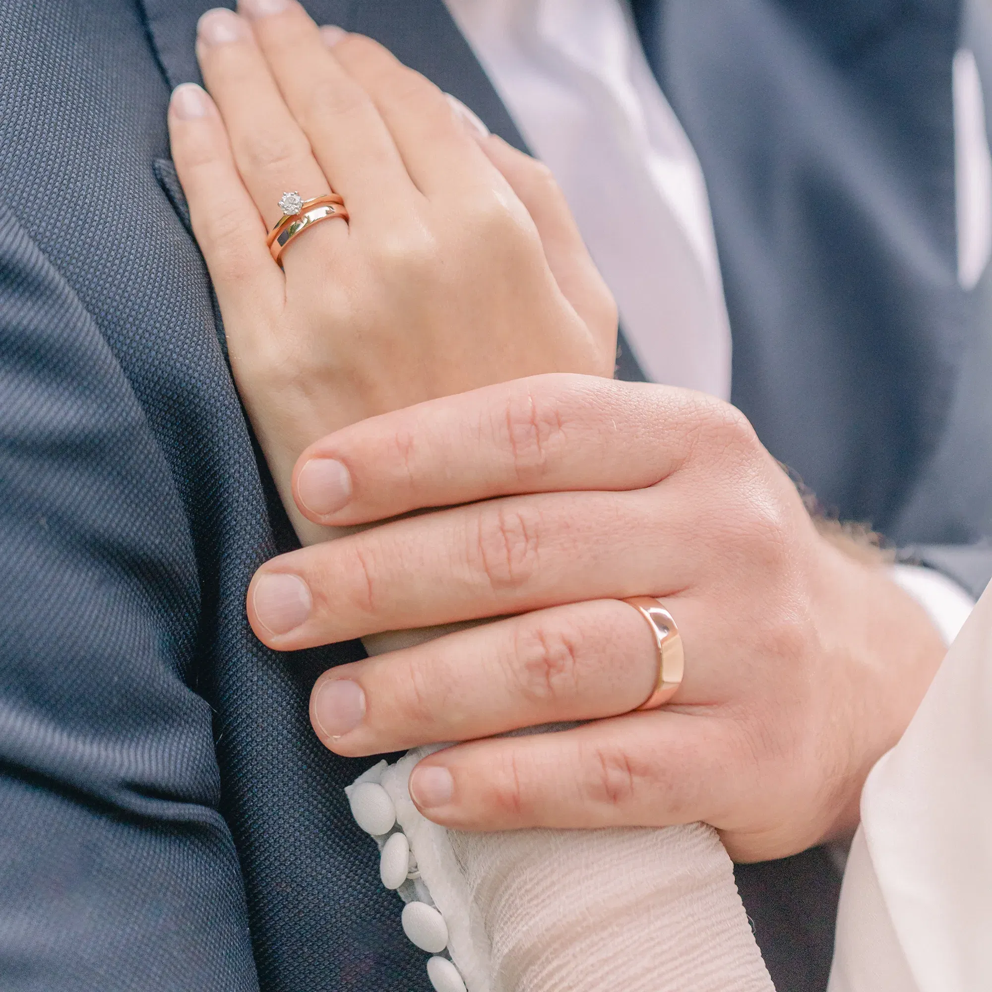 Mann und Frau halten sich die Hände, an ihren Fingern steckt ein Trauring.