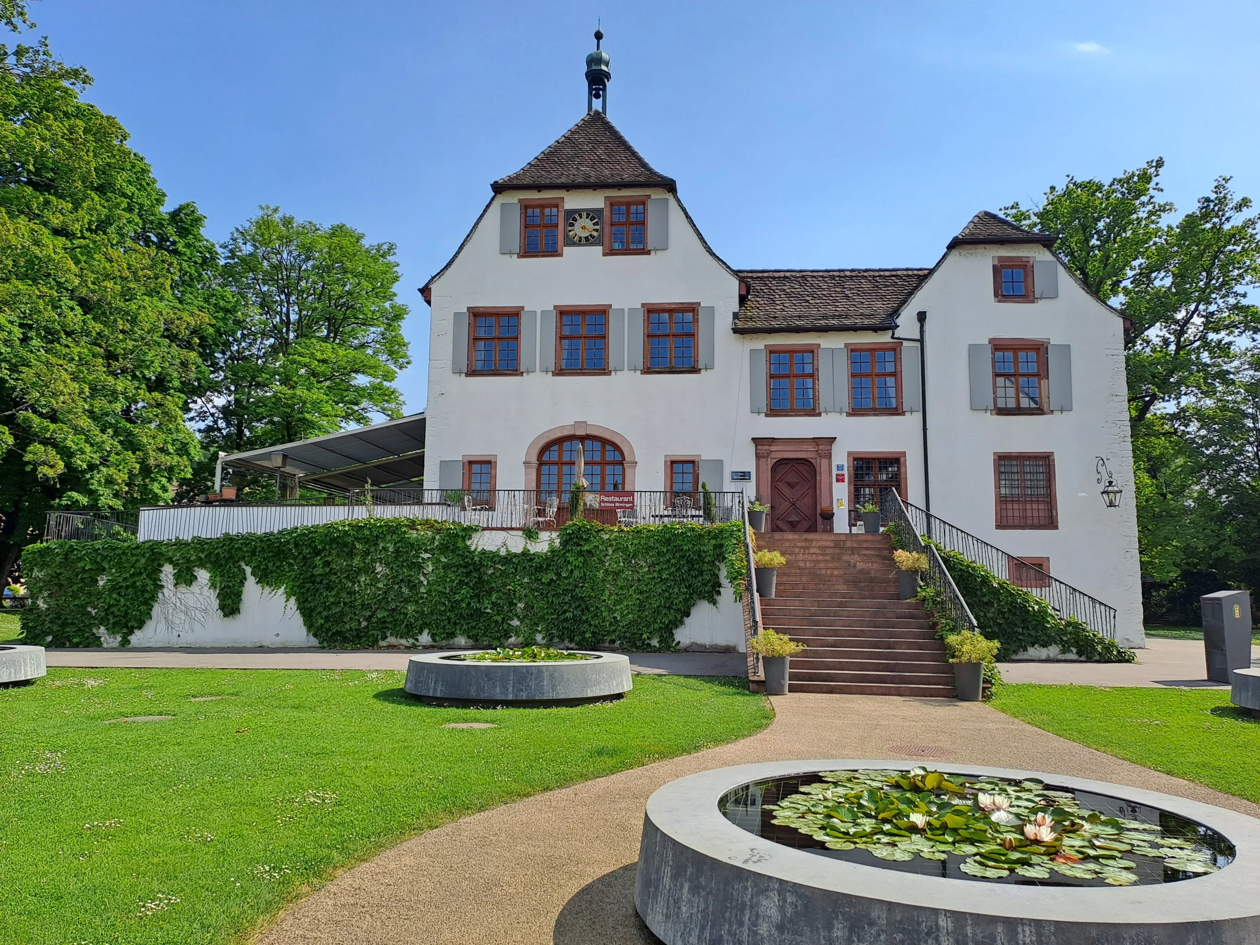 Schloss Binningen unter blauem Himmel im grün umgeben.