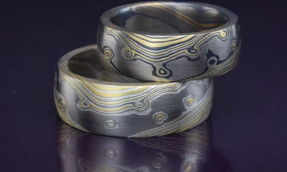 Auffällige Eheringe aus einem Gemisch von Gold und Silber, mit einem besonderen Linienmuster, das sich spiralförmig über die Oberfläche zieht.