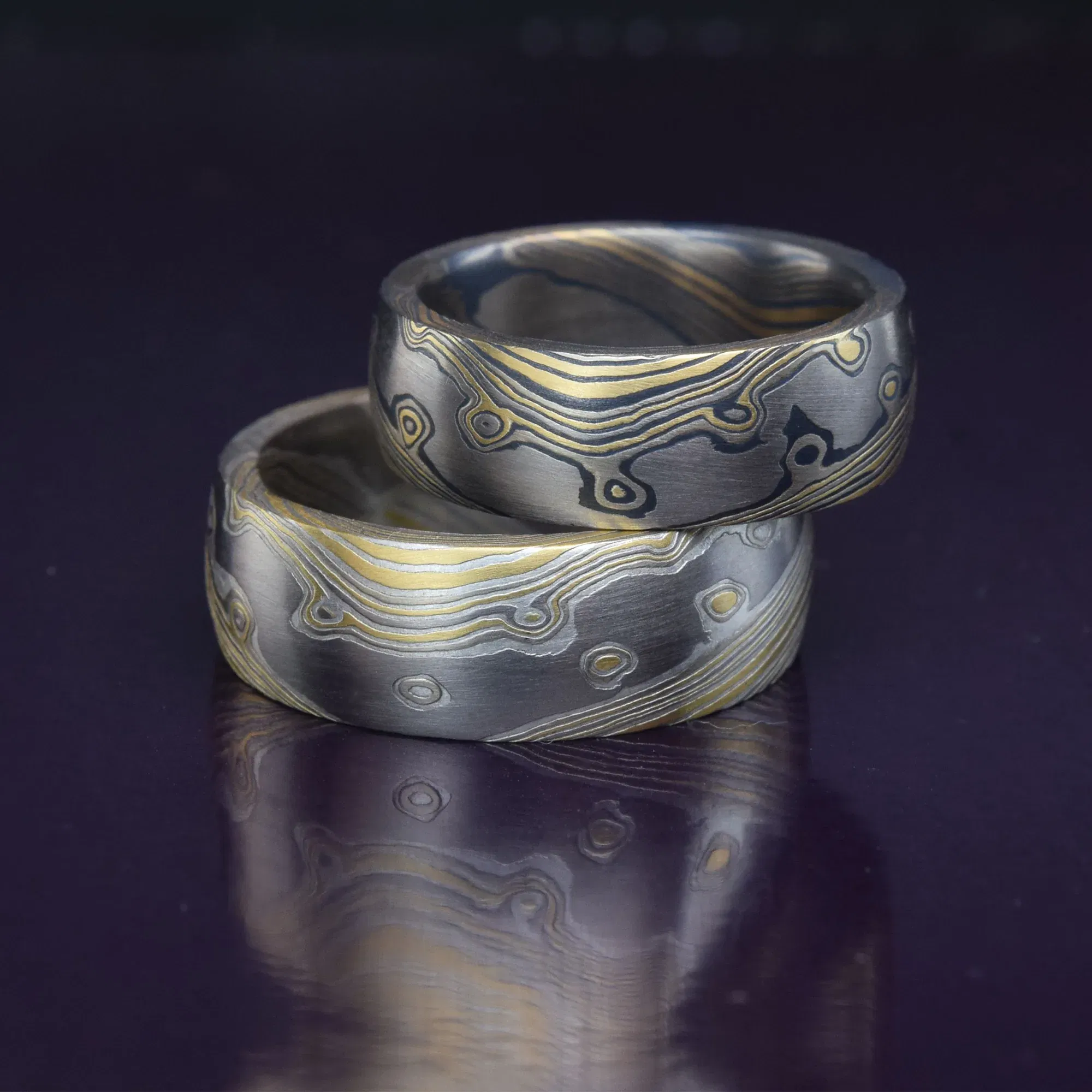 Auffällige Eheringe aus einem Gemisch von Gold und Silber, mit einem besonderen Linienmuster, das sich spiralförmig über die Oberfläche zieht.