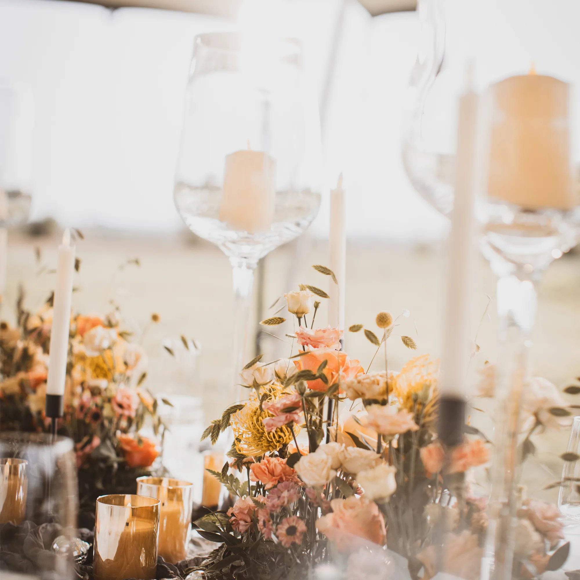 Ein wunderschön gedeckter Hochzeitstisch mit zarten Blumenarrangements und hohen Kerzenhaltern, die im weichen Licht der untergehenden Sonne leuchten.