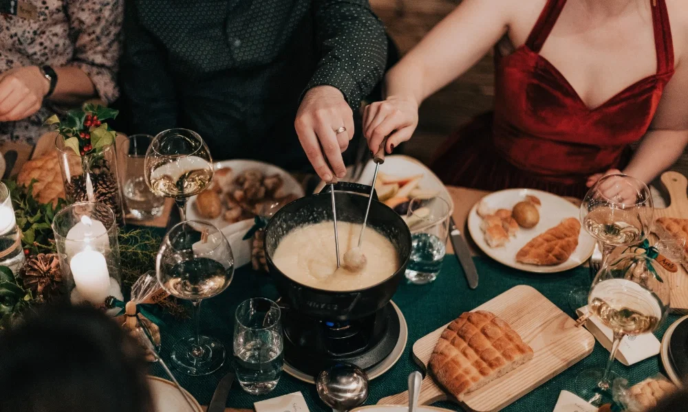 Das Hochzeitsessen Fondue, das Brautpaar hält das Brot in das Käsefondue