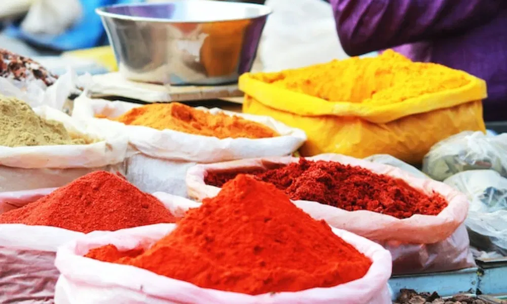 Bunte Auswahl an gemahlenen Gewürzen in Plastiksäcken auf einem Basar – von kräftigem Rot bis leuchtendem Gelb.