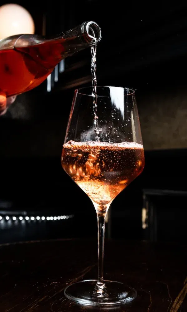 Spritziger Roséwein fließt in ein stilvolles Glas, perfekt eingefangen mit glitzernden Reflexionen im Abendlicht.