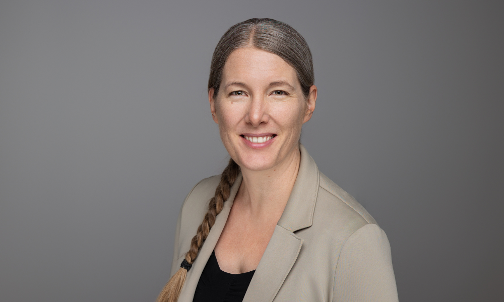 Die Hochzeitsfotografin lachend auf dem Bild mit einem grauen Hintergrund