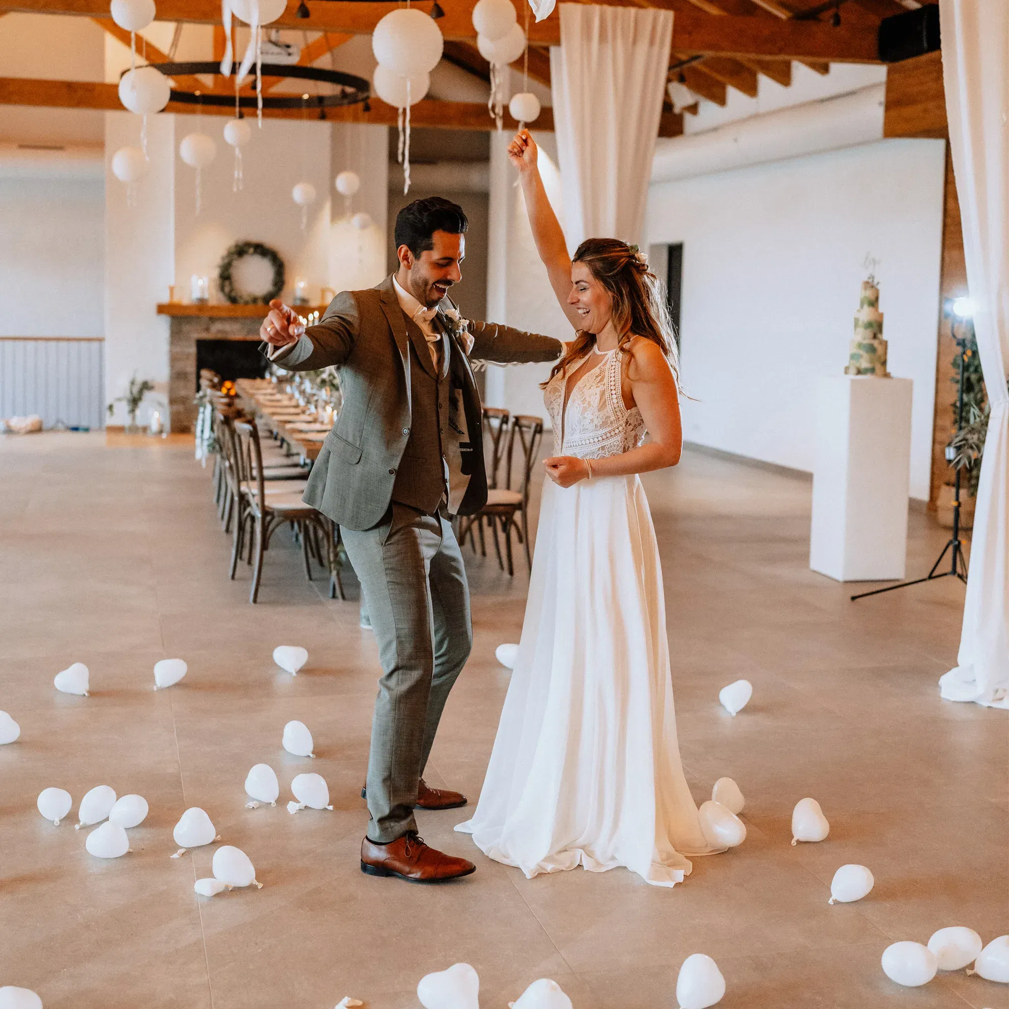 Braut und Bräutigam tanzen in einem eleganten Hochzeitssaal, dekoriert mit weißen Laternen und Luftballons, während sie den ersten Tanz als frisch verheiratetes Paar genießen.
