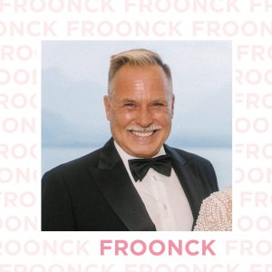 Froonck, professioneller Hochzeitsplaner und Trauredner, in einem stilvollen Porträt vor einem Schriftzug-Hintergrund. Sein Lächeln zeigt seine Leidenschaft für die Hochzeitsbranche.