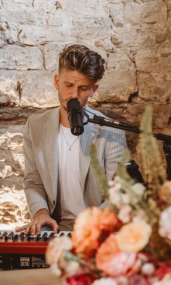 Live-Musik bei der Trauung: Künstler in stimmungsvoller Kulisse mit Mikrofon und Blumenarrangements.