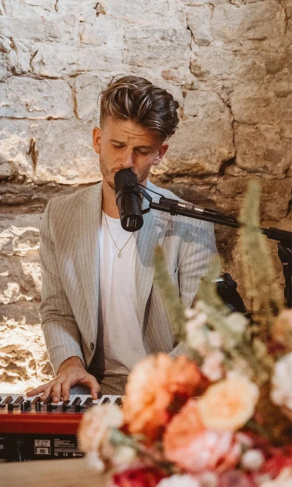 Live-Musik bei der Trauung: Künstler in stimmungsvoller Kulisse mit Mikrofon und Blumenarrangements.