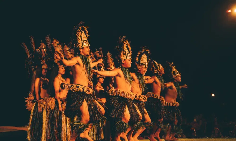 Tänzer in traditionellen Kostümen führen bei Nacht eine eindrucksvolle polynesische Choreografie auf.