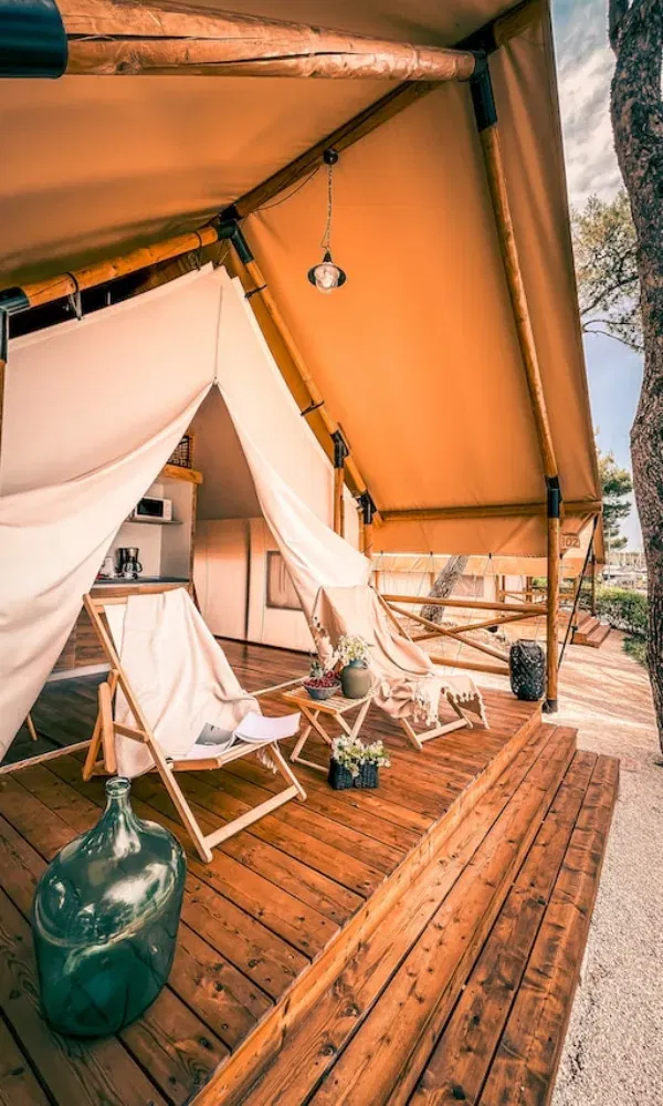 Gemütliche Outdoor-Lounge in einem Glamping-Zelt: Holzboden, Sitzgelegenheiten, Naturflair und stilvolle Einrichtung laden zum Entspannen ein.