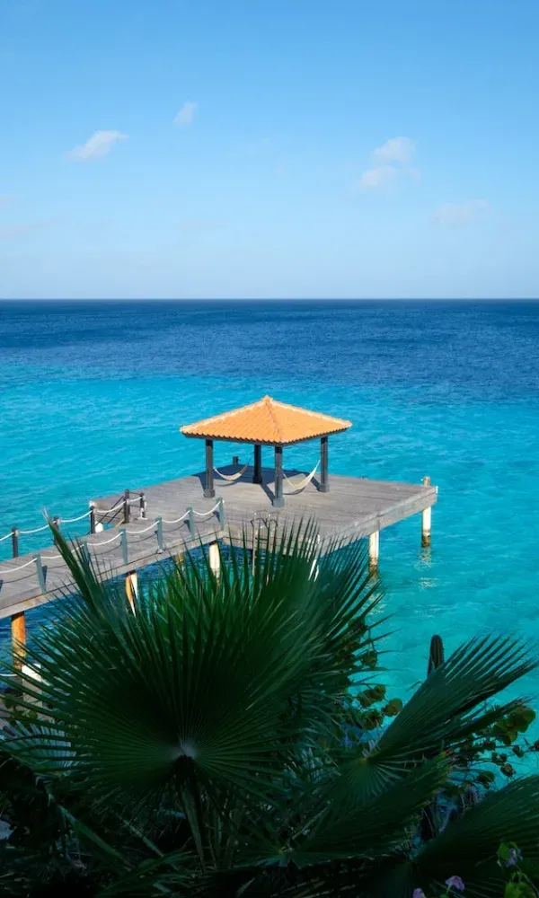 Ein Pavillon auf einem Holzsteg lädt zum Verweilen über karibischem Wasser ein – ein perfekter Ort zum Entspannen mit Meerblick.