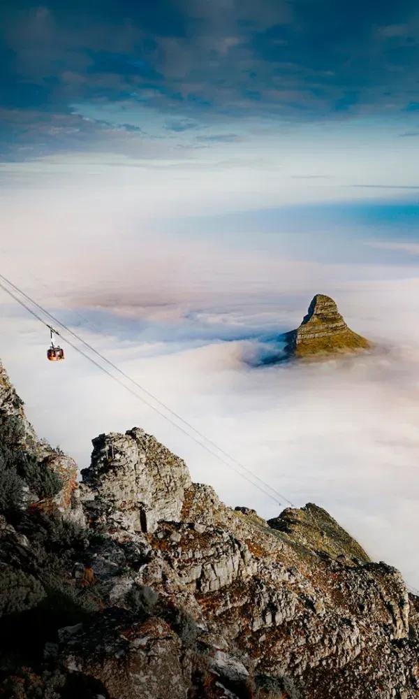 Eine Seilbahn schwebt durch die Wolkenlandschaft über Kapstadts Bergwelt – ein atemberaubendes Panorama mit Blick auf den Lion’s Head.