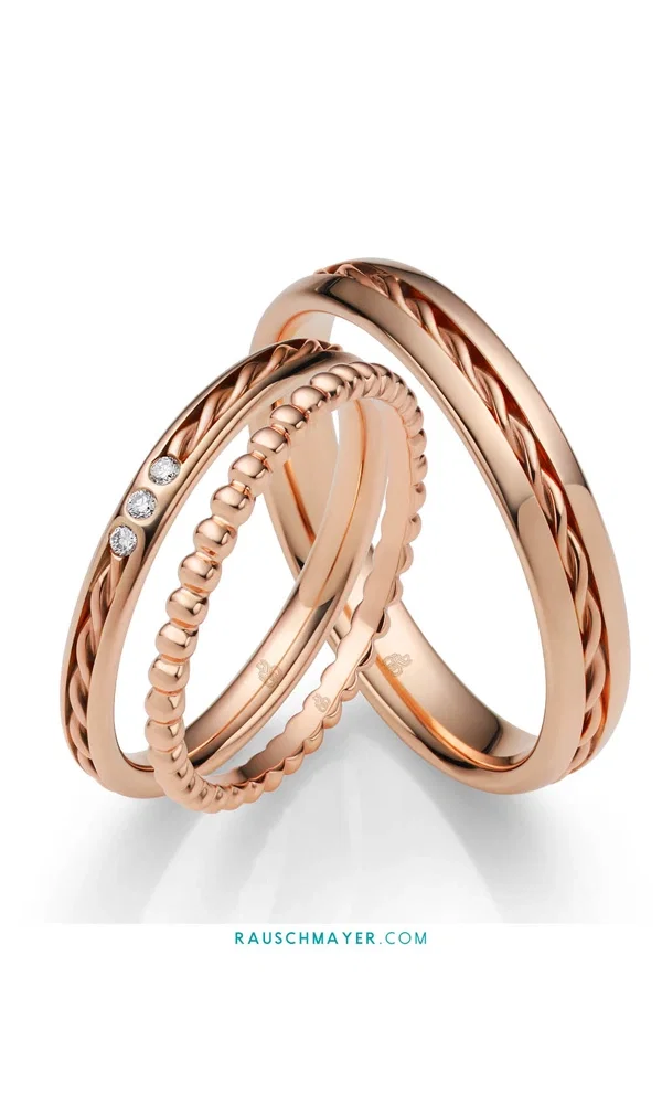 Ein Set aus kunstvoll gestalteten Ringen in warmem Roségold, bestehend aus einem schlichten Hochzeitsring, einem geflochtenen Modell sowie einem zarten Memoire-Ring mit funkelnden Brillanten.