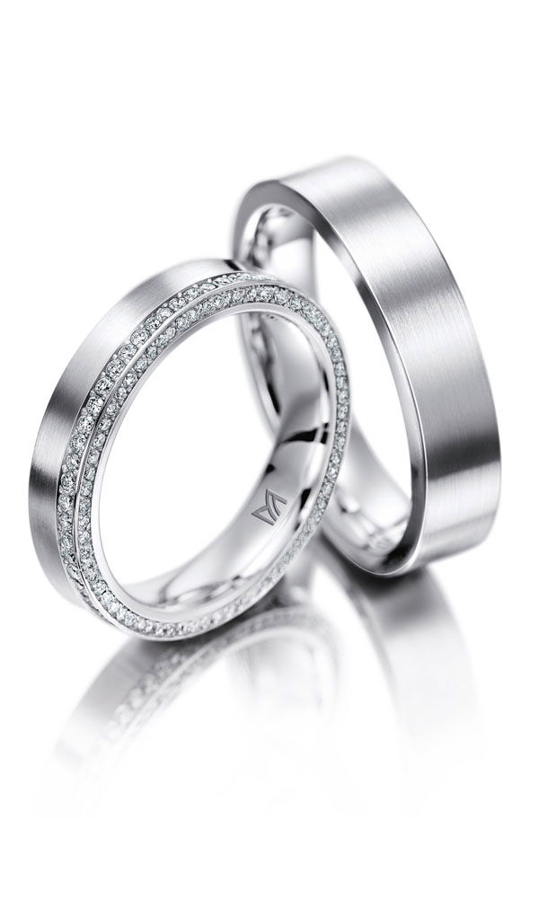 Elegante Partnerringe aus Platin mit seidiger, mattschimmernder Oberfläche. Der Damenring ist mit unzähligen kleinen Brillanten besetzt, die ihm einen luxuriösen Look verleihen, während der Herrenring klassisch gehalten ist.