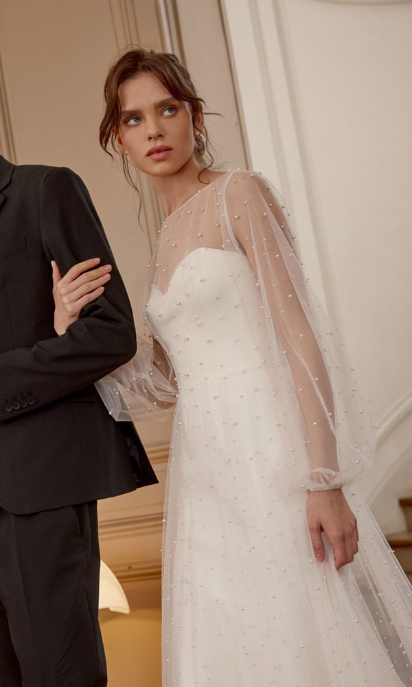 Schlichtes, aber glamouröses Brautkleid mit perlenbesetztem Stoff und transparenten Details, das eine zeitlose Eleganz ausstrahlt.