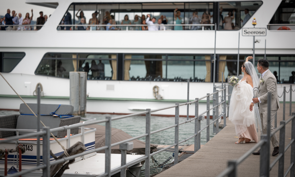 Das Brautpaar winkt seinen Gästen auf dem Schiff zu