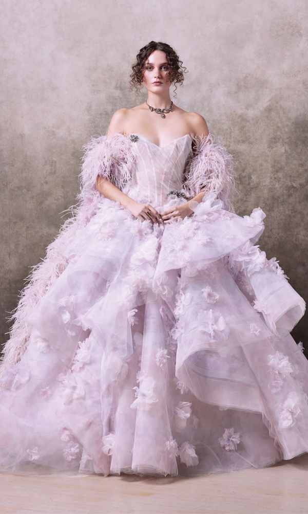 Elegantes Couture-Brautkleid mit aufwendig besticktem Tüll, romantischen Blumenverzierungen und einem dramatischen Federbesatz. Das schulterfreie Oberteil verleiht eine moderne, feminine Note.