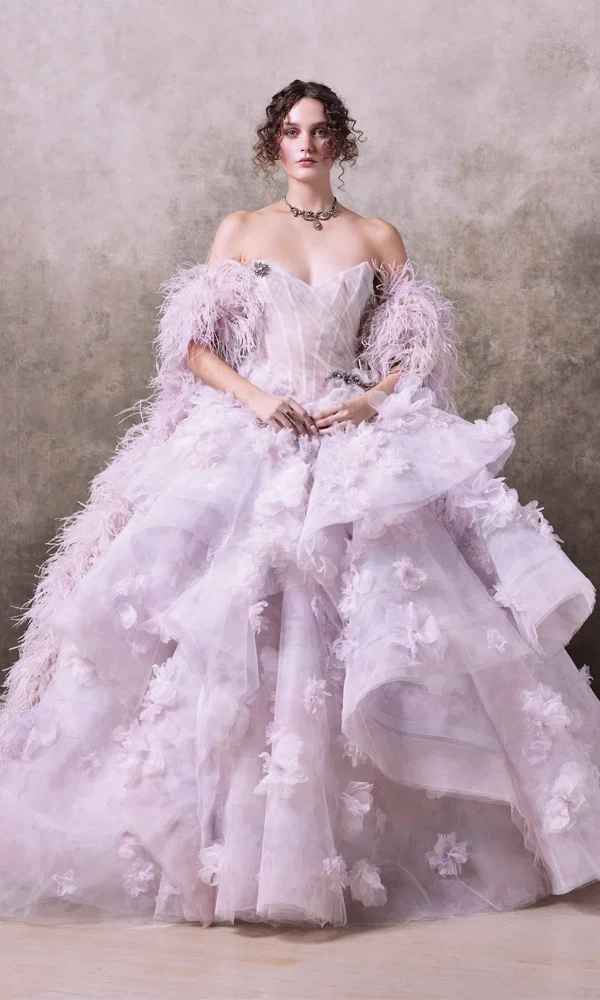 Elegantes Couture-Brautkleid mit aufwendig besticktem Tüll, romantischen Blumenverzierungen und einem dramatischen Federbesatz. Das schulterfreie Oberteil verleiht eine moderne, feminine Note.