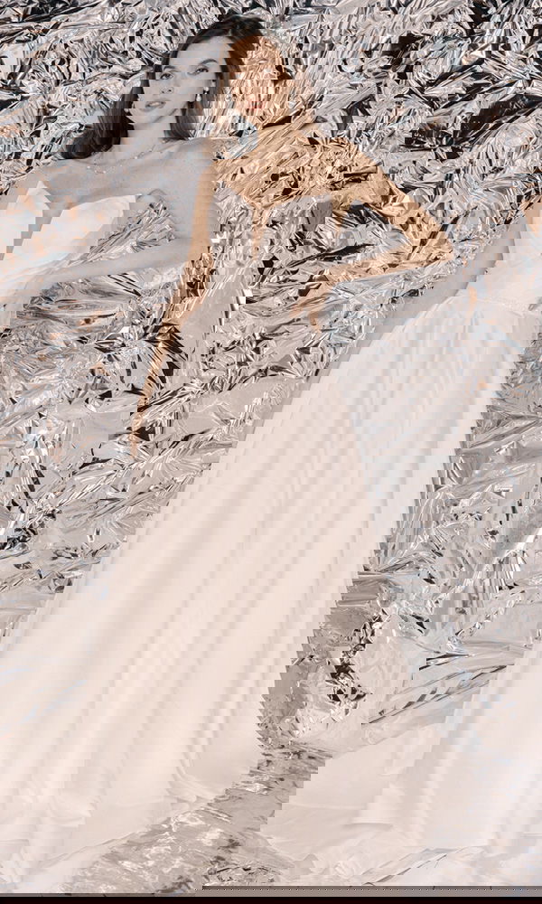 Zeitloses Brautkleid mit voluminösem Rock und dezentem Design, perfekt inszeniert vor einer schimmernden, futuristischen Kulisse.