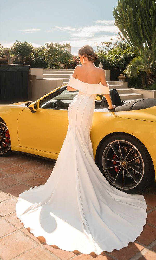 Stilvolle Braut im Designer-Brautkleid vor gelbem Porsche – perfekte Verbindung aus Glamour und moderner Hochzeitsmode.