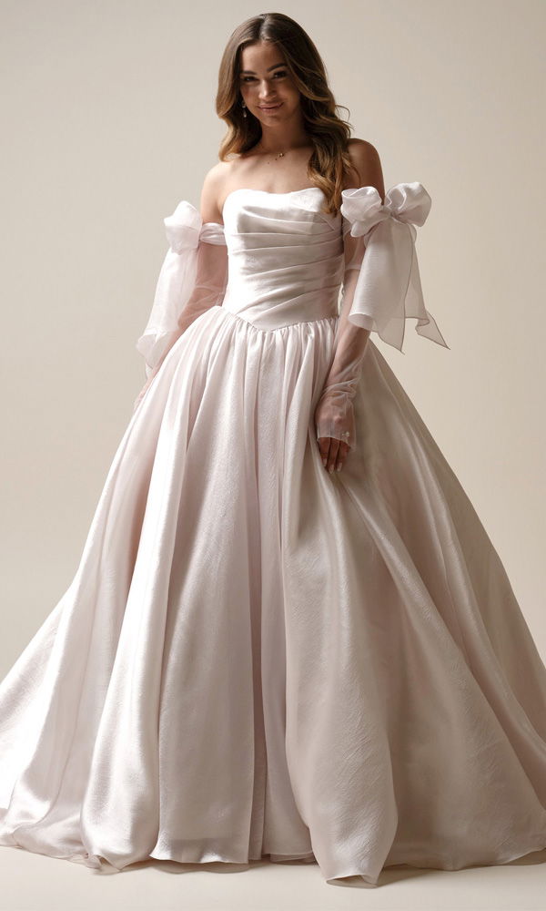 Prinzessinnen-Brautkleid mit Glanzstoff und abnehmbaren Schleifenärmeln – moderner Märchen-Look für den großen Tag.