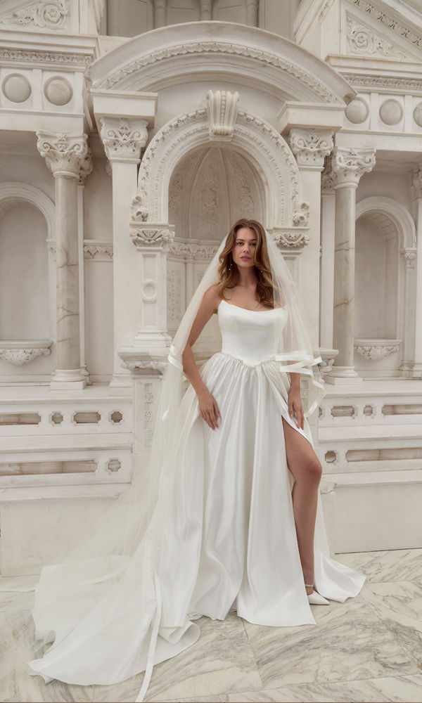 Traumhaftes Brautkleid mit klassischem Ausschnitt und moderner Note, stilvoll präsentiert in einer kunstvollen, barocken Umgebung.