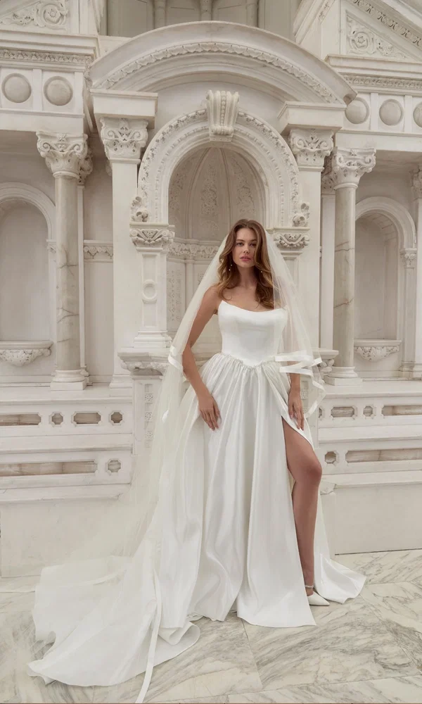 Traumhaftes Brautkleid mit klassischem Ausschnitt und moderner Note, stilvoll präsentiert in einer kunstvollen, barocken Umgebung.