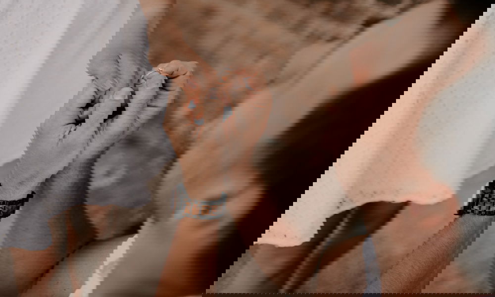 Ein Mann kniet und hält die Hand seiner Partnerin, während er ihr zärtlich einen Verlobungsring an den Finger steckt, ein Symbol für Liebe und Engagement.