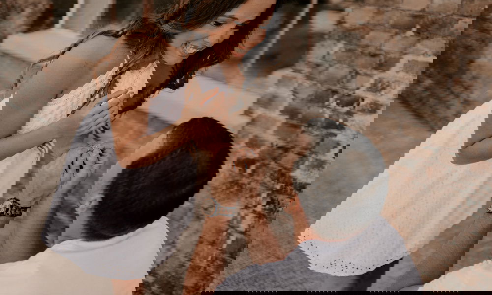 Glücklicher Moment eines Heiratsantrags: Eine Frau in einem weißen Kleid lächelt überwältigt, während ein Mann kniet und ihre Hand hält.