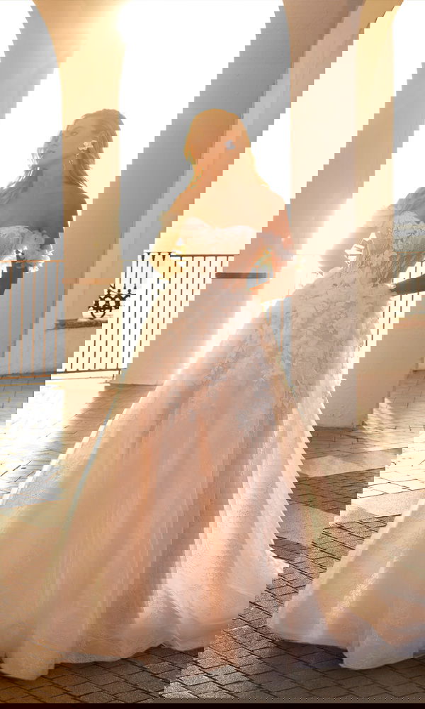 Verspieltes Brautkleid mit Blumenapplikationen und transparenter Corsage – träumerischer Look für eine Hochzeit am Meer.