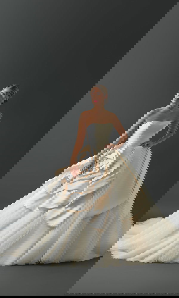 Großartiges Brautkleid mit voluminöser Silhouette und floraler Drapierung, das klassische Eleganz und moderne Extravaganz kombiniert.