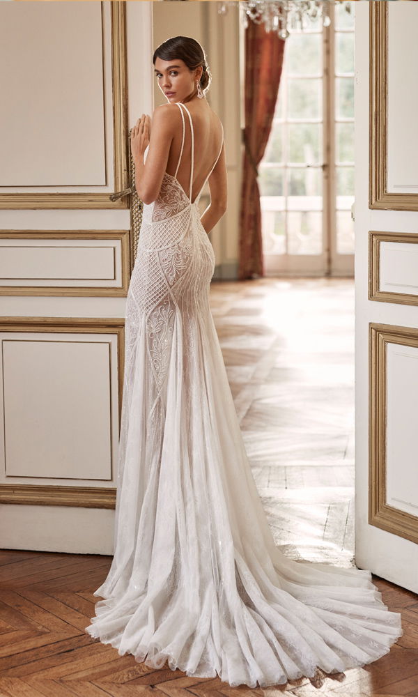 Traumhaftes Brautkleid mit transparenten Spitzendetails und langer Schleppe, das eine feminine Eleganz in einem luxuriösen Raum unterstreicht.