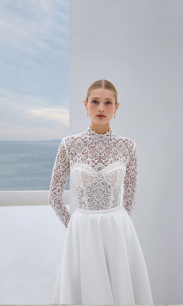 Zeitloses Kleid mit romantischem Spitzenmuster und minimalistischem Rock, perfekt für eine Hochzeit mit Meerblick.