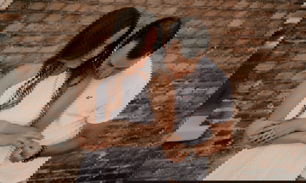 Ein Paar teilt einen zärtlichen Augenblick. Der Mann hält die Hand der Frau, die stolz ihren neuen Verlobungsring trägt.