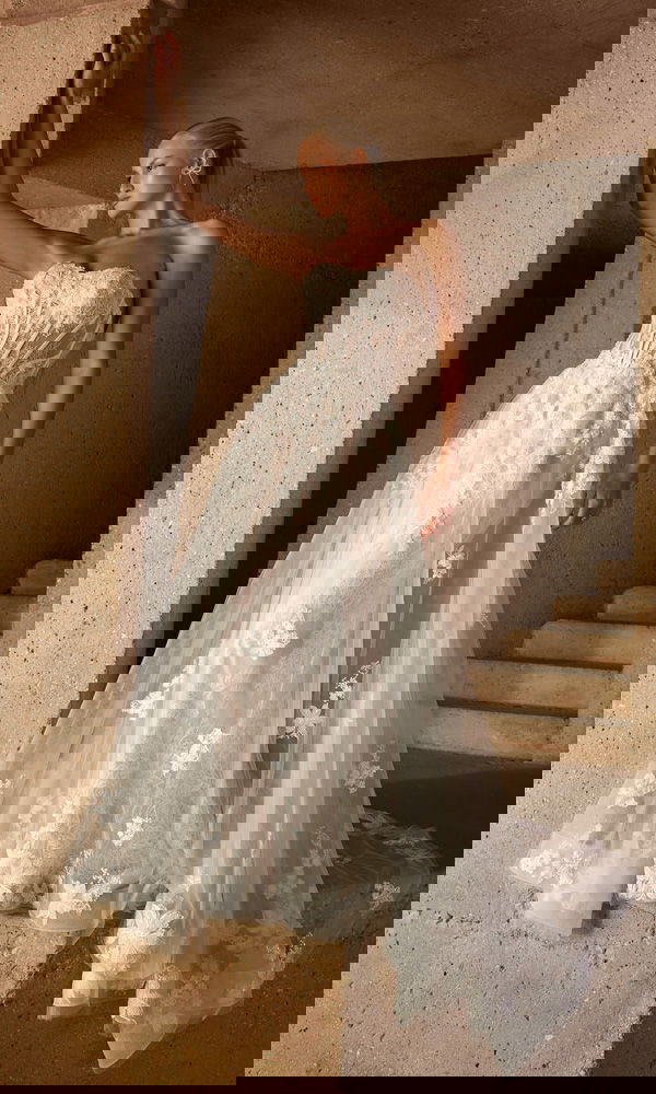 Designer-Brautkleid mit figurbetontem Schnitt und kunstvoller Spitze, fotografiert in einem steinernen Treppenaufgang.