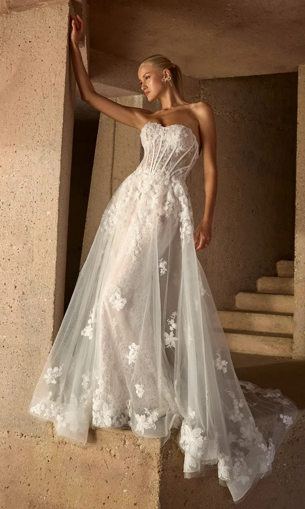 Designer-Brautkleid mit figurbetontem Schnitt und kunstvoller Spitze, fotografiert in einem steinernen Treppenaufgang.