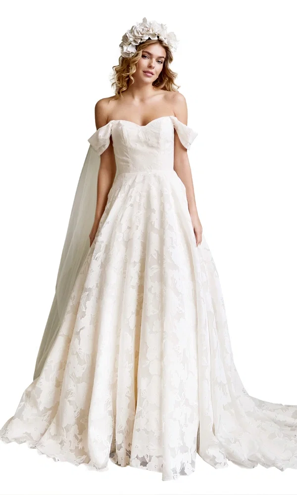 Boho-inspiriertes Hochzeitskleid mit zartem Blumenmuster und Off-Shoulder-Schnitt – kombiniert mit Blumenkranz für einen natürlichen Look.